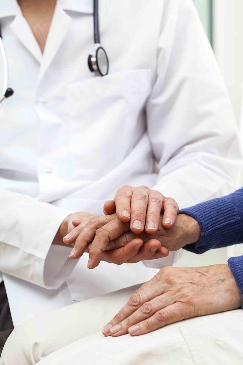 Closeup image of a health care provider holding a woman's hand