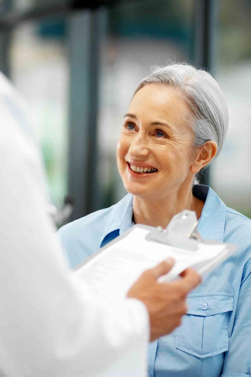 an older woman smiles as while speaking to a health care provider