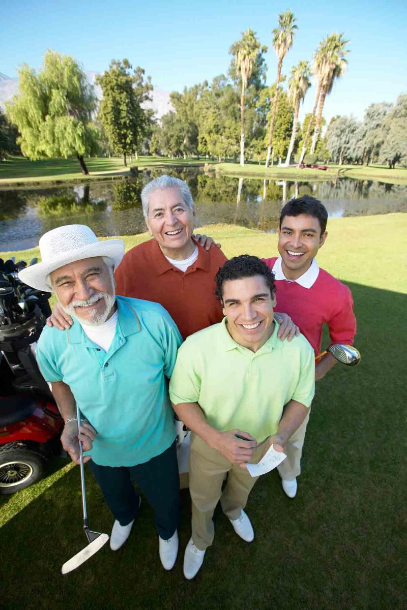 four men of different ages standing together on a golf course
