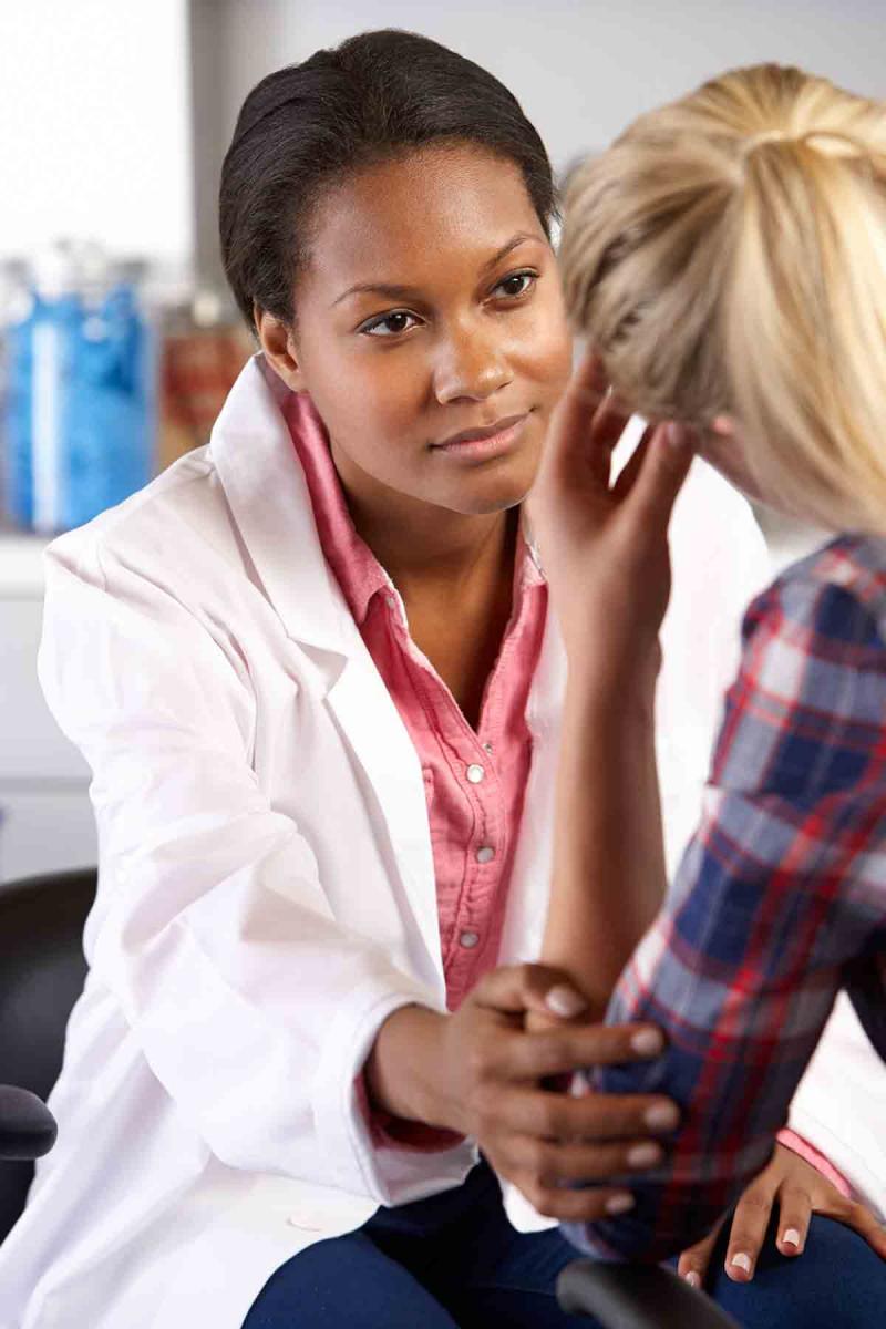 a doctor listens to her young female patient