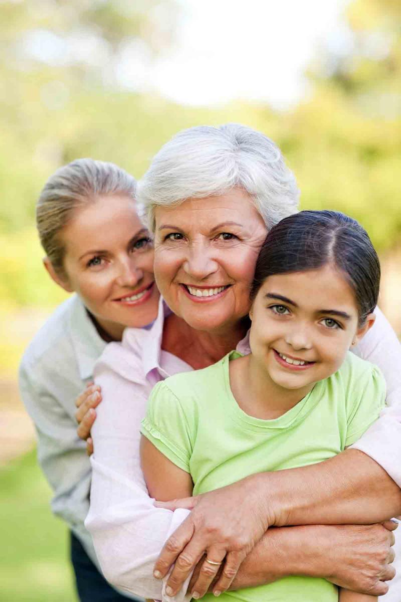 three generations of women smile and hug outdoors